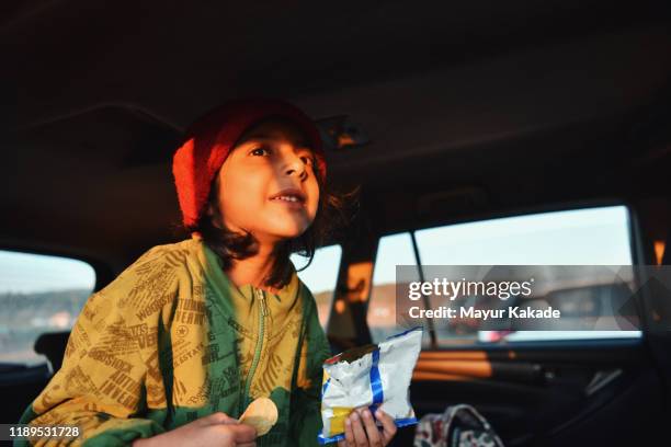 girl eating chips while sitting in the car - patatas fritas tentempié fotografías e imágenes de stock