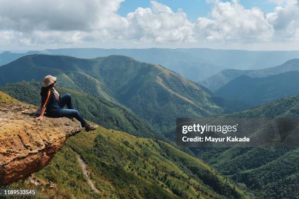 single woman traveller looking at valley views while sitting on the cliff - indian ethnicity travel stock pictures, royalty-free photos & images