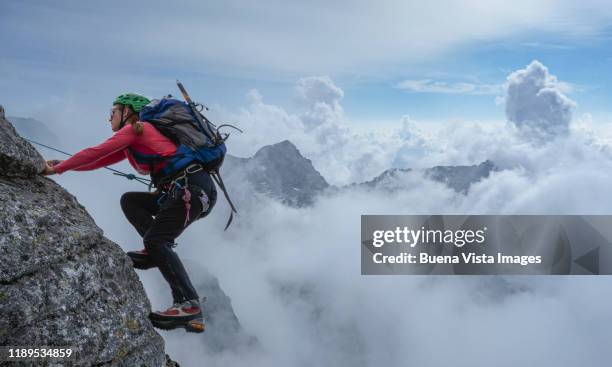 female climber on a rocky wall - mountain climber stock-fotos und bilder