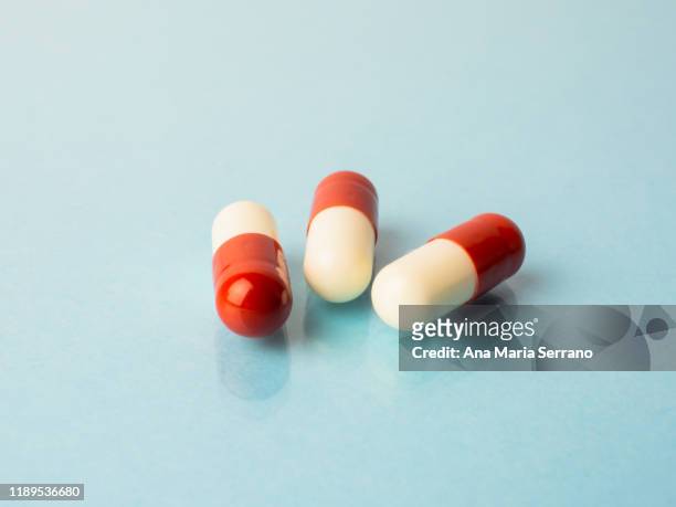 several pills reflected on a pastel blue background with mirror effect - mdma stock pictures, royalty-free photos & images