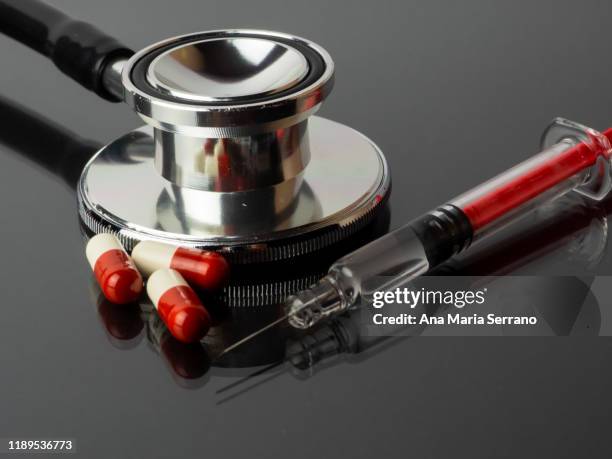 a syringe, stethoscope and several pills reflected on a gray background with mirror effect - lethal injection stock pictures, royalty-free photos & images
