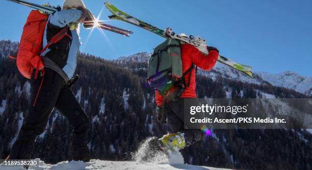 ski couple traverse snowslope above valley - ski pants stockfoto's en -beelden