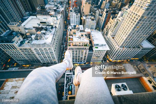 personal perspective of feet hanging down from the rooftop of a high rise in manhattan, new york city - look down stock pictures, royalty-free photos & images