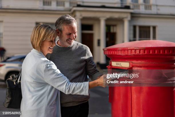 happy adult couple putting a letter in the mail - sending stock pictures, royalty-free photos & images