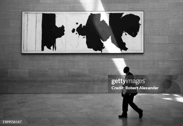 Museum guard walks past a painting by Robert Motherwell, titled 'Reconciliation Elegy', as a beam of sunlight strikes the wall at the National...