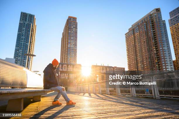 man sitting on a bench admiring the sunrise from a pier in long island, new york state - insel long island stock-fotos und bilder