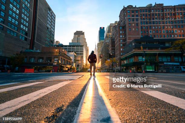 one person crossing a junction in manhattan at sunrise, new york city - sunrise new york stock-fotos und bilder