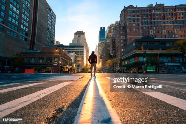 one person crossing a junction in manhattan at sunrise, new york city - vision and mission stockfoto's en -beelden