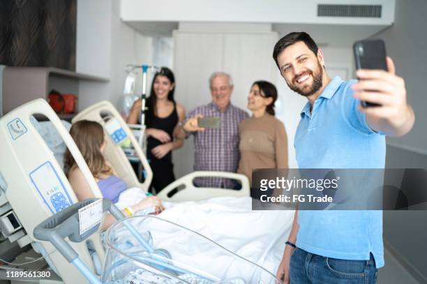 father taking a selfie with his newborn and family - hospital visit stock pictures, royalty-free photos & images