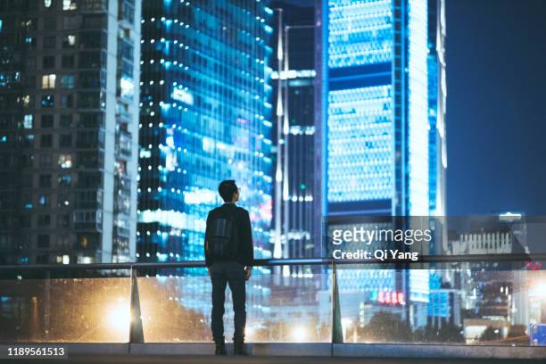 young businessman looking at beautiful shanghai night scene - retrato espalda fotografías e imágenes de stock