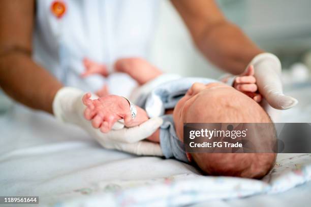 krankenschwester untersucht ein neugeborenes im krankenhaus - baby delivery stock-fotos und bilder