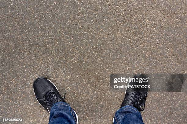 low section of teenager standing on asphalt road - schuhe von oben stock-fotos und bilder