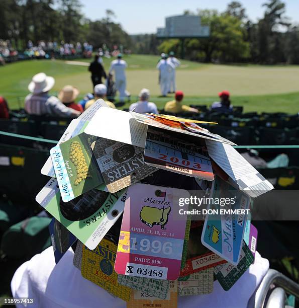 Fan wears a hat covered in Masters passs at the 18th green during the first round of the Masters golf tournament at Augusta National Golf Club on...