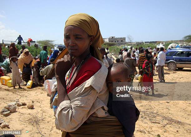 Picture taken on July 12, 2011 shows a displaced woman carrying her baby as she arrives at a new camp in southern Mogadishu, where the Somalia's...