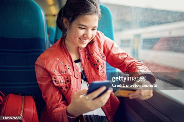 young teenage girl is shopping online/making reservation in the train - mobile payment stock pictures, royalty-free photos & images