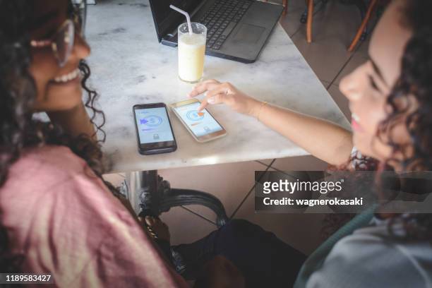 young women sending money through digital wallet, using wireless technology - sending payment stock pictures, royalty-free photos & images