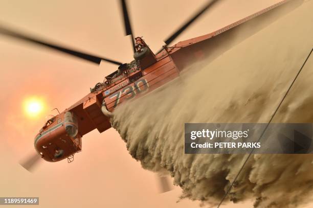 Helicopter drops fire retardent to protect a property in Balmoral, 150 kilometres southwest of Sydney on December 19, 2019. - A state of emergency...