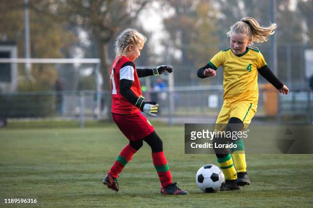meisjes spelen voetbal tijdens een voetbalwedstrijd - match sport stockfoto's en -beelden