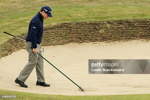 Tom Watson of the USA rakes a bunker during the final practice round during The Open Championship at Royal St. George's on July 13, 2011 in Sandwich,...