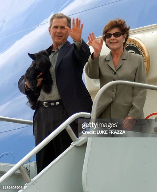 President George W. Bush, holding pet dog Barney, and his wife Laura wave from Air Force One 15 April 2001 at Fort Hood Army Base in Texas. The...