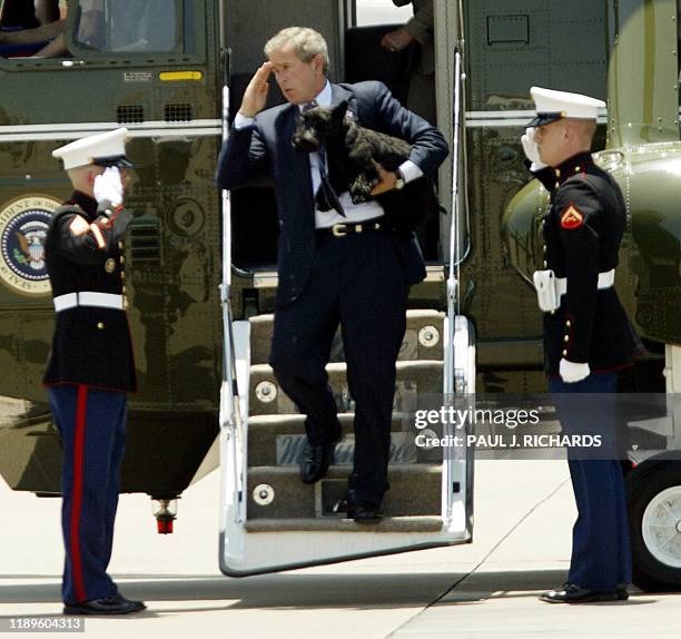 President George W. Bush salutes his Honor Guard with one hand and holds his dog Barney with the other after leaving his Crawford, Texas, ranch...