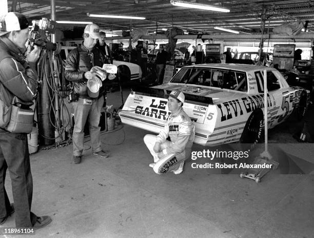 Driver Geoff Bodine poses with a variety of sponsor caps for the benefit of a photographer in the Daytona International Speedway garage prior to the...