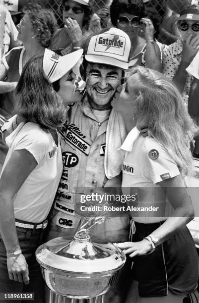 Driver Bobby Allison gets a kiss on the cheek from the trophy girls as they celebrate his 1982 Firecracker 400 win in Victory Lane on July 4, 1982 at...