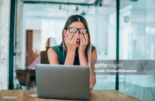empresaria con dolor de cabeza sentada en el escritorio - frustración fotografías e imágenes de stock