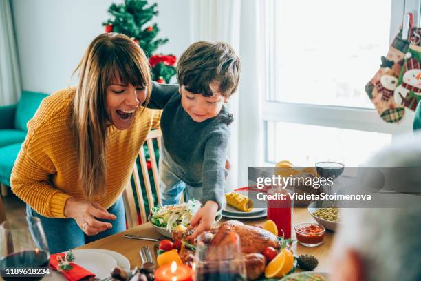 glückliche mutter und ihr sohn spaßig beim halten gerösteten truthahn bein - christmas table turkey stock-fotos und bilder