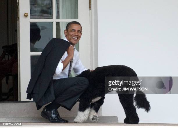 President Barack Obama pets the family dog, Bo, upon his return to the White House in Washington, DC, on March 15, 2012. AFP PHOTO/Jim Watson