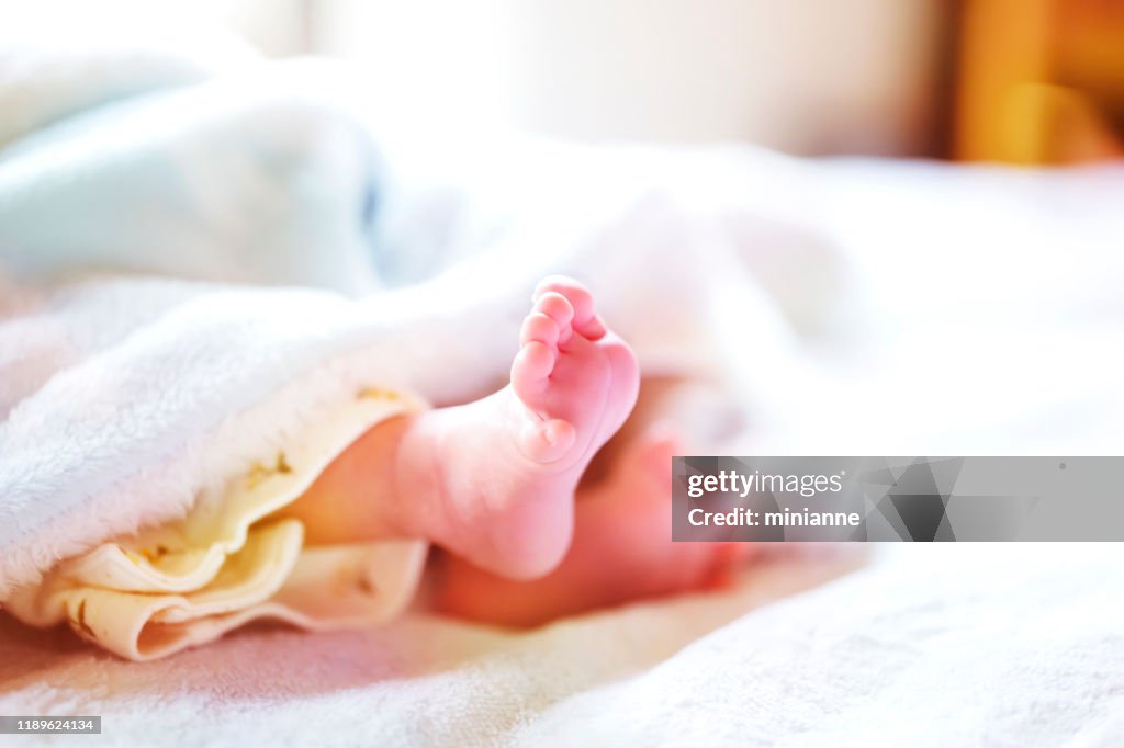 Newborn baby on a white and light blue blanket - tiny baby feet.