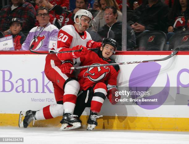 Dylan McIlrath of the Detroit Red Wings hits Brett Seney of the New Jersey Devils during the second period at the Prudential Center on November 23,...