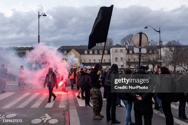 In the foreground, anarchist activists wave a large black flag while in the background railway workers burn red smoke on Thursday 19 December 2019,...