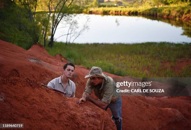 Paleontologists Jose Darival Ferreira and Rodrigo Temp Muller examine a newly found fossil at an excavation site in Agudo, Brazil, on December 3,...