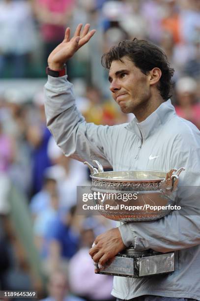 Rafael Nadal of Spain waves to the crowd as he holds the Coupe de Mousquetaires after victory in his men's singles final match against Novak Djokovic...