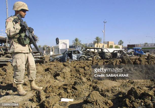 Soldier looks at the 10-meter wide by 5-meter deep crater caused by the explosion of a suicide bomb outside the police station of Baquba, 60km north...