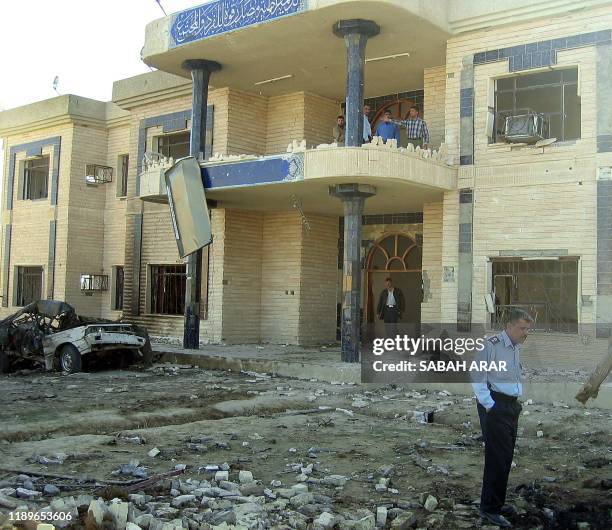 An Iraqi police officer stands in front of the police station in Baquba, 60km north of Baghdad, after a suicide bomb attack 22 November 2003. The...