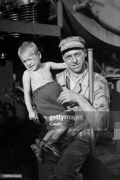 Railway worker poses with a little boy repatriated from German concentration camp of Buchenwald in front of the train that brought them back from...