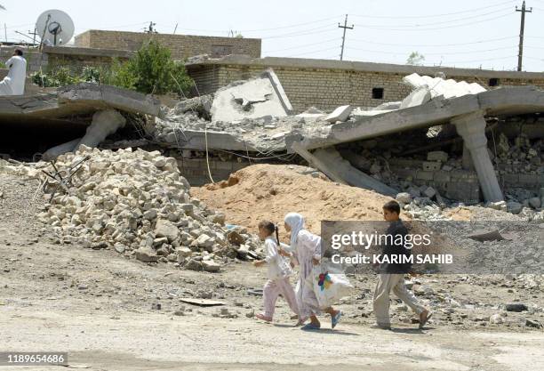 Two Iraqi girls walk 05 May 2004 past a house destroyed during battles between US marines and insurgents in the restive city of Fallujah. US-trained...