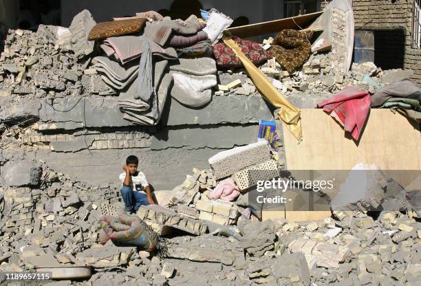 An Iraqi boy sits on the rubble of his destroyed home following a US air strike in the restive city of Fallujah, 13 September 2004. At least 15...
