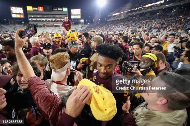 Quarterback Jayden Daniels of the Arizona State Sun Devils is surrounded by fans on the field after defeating the Oregon Ducks in the NCAAF game at...