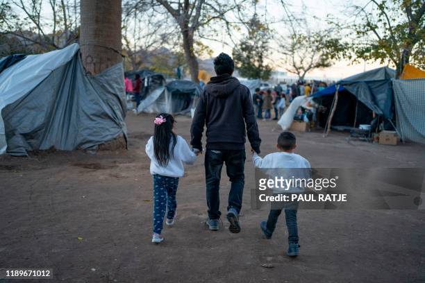 Man from Michoacan State walks with his daughter and son through the campsite of Mexican asylum seekers at Chamizal Park in Ciudad Juarez, Mexico, on...