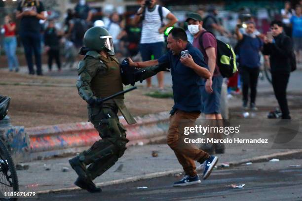 Protester tries to avoid a riot police officer during a protest against the government of President Sebastian Piñera on December 20, 2019 in...