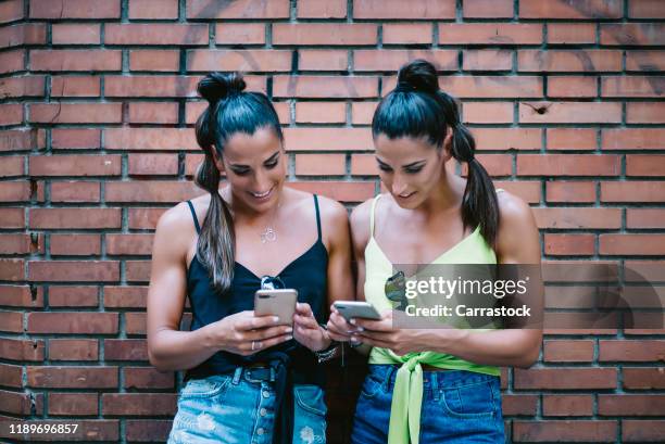 two beautiful twin sisters take a picture with mobile phone. - twins stock pictures, royalty-free photos & images