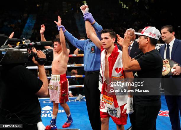 Referee Jay Nady holds up the arms of Julio Ceja and Brandon Figueroa after their super bantamweight bout ended in a draw at MGM Grand Garden Arena...