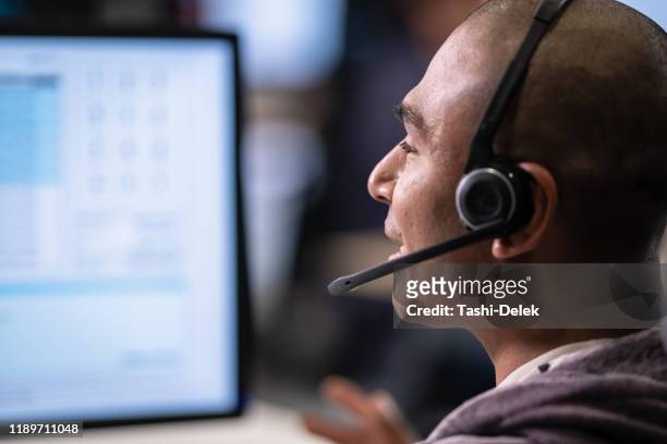 man talking to a customer over a headset - call center agents imagens e fotografias de stock