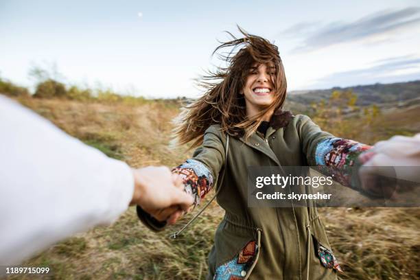 cheerful woman having fun while spinning with her boyfriend in nature. - autumn fun stock pictures, royalty-free photos & images