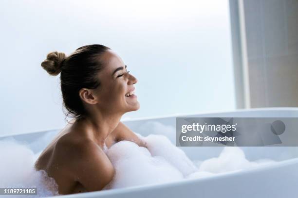 jeune femme heureuse appréciant dans le bain moussant avec ses yeux fermés. - beautiful woman bath photos et images de collection