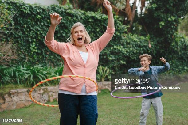 grootmoeder en kleinzoon spelen met hula hoepels buiten - hoelahoep stockfoto's en -beelden