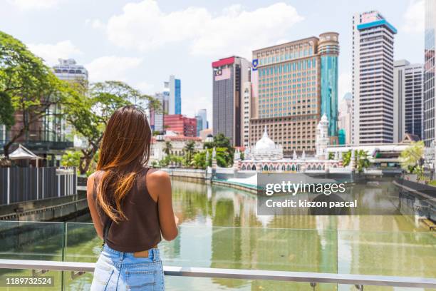 asian woman looking at downtown kuala lumpur during a sunny day . - kuala lumpur city stock pictures, royalty-free photos & images